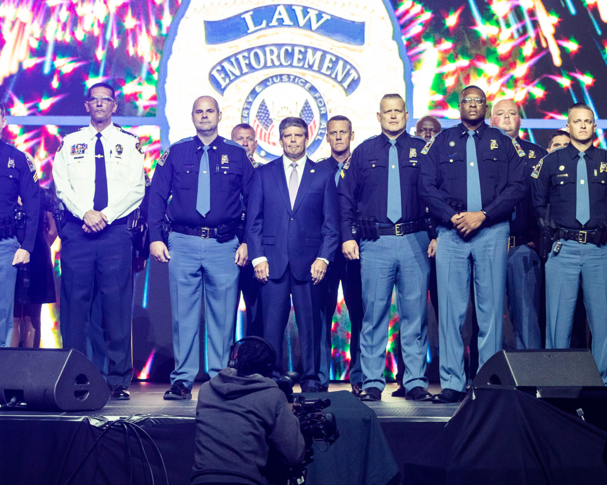 Center, Hal Taylor, Secretary of Law Enforcement of the Alabama Law Enforcement Agency (ALEA) stands with 150 law enforcement officers on stage during the 2022 Faulkner Benefit Dinner. 