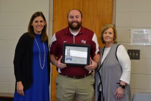 Man Holding Framed Certificate Between Two Women