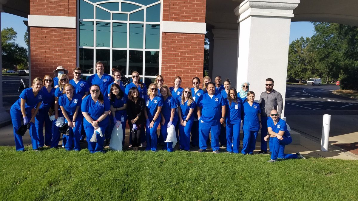 Students with the Physician Assistant program pose for a picture in front of Faulkner's front entrance after volunteering to pick up trash along Atlanta Highway.