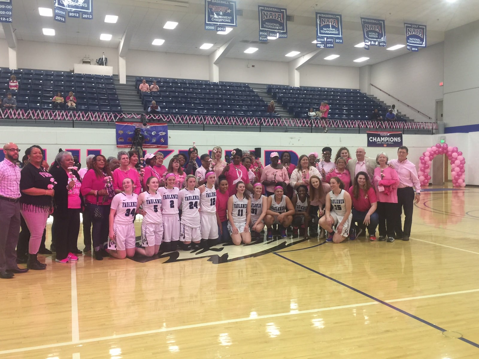 Breast Cancer survivors pose with the Faulkner Women's Basketball team during their PinkOut game in 2020.