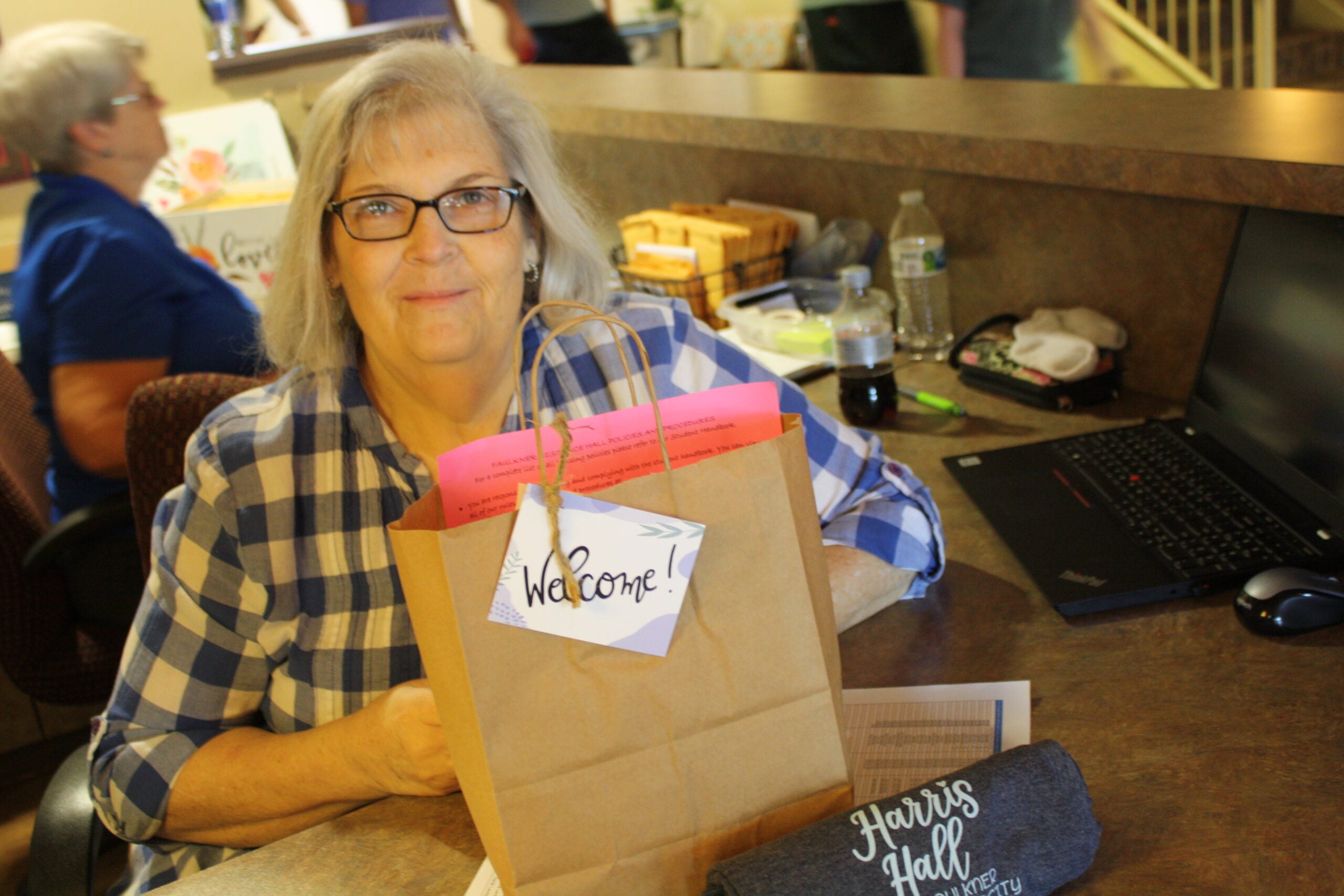 Peggy Oliver sits at the front desk of the women's dormitory with a gift bag to welcome freshmen girls to their new home away from home.