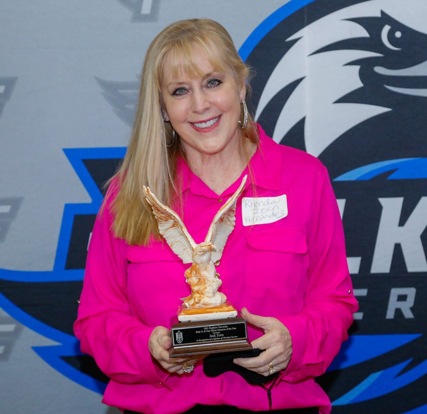 Rhonda Fernandez holds her father's Alumnus of the Year Award, an Alabama Clay eagle with its wings in flight.