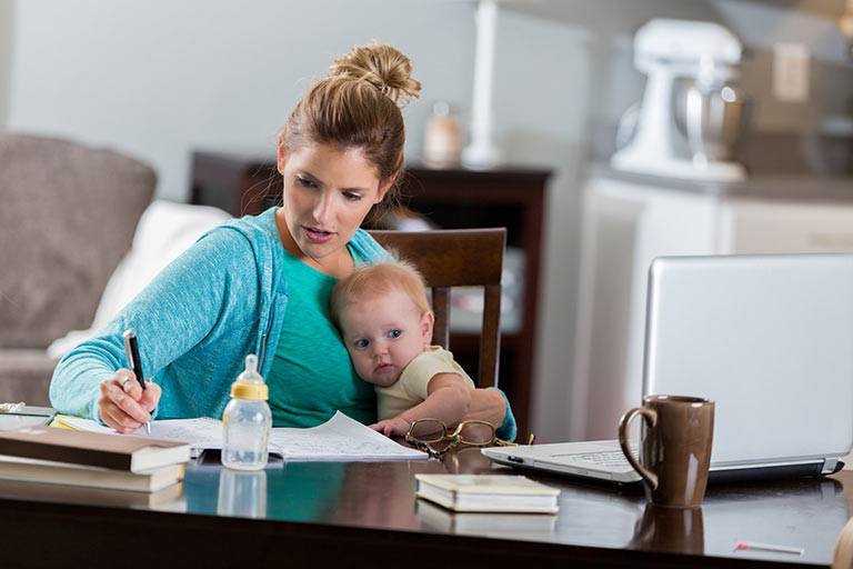 woman-holding-a-child-while-working-on-computer