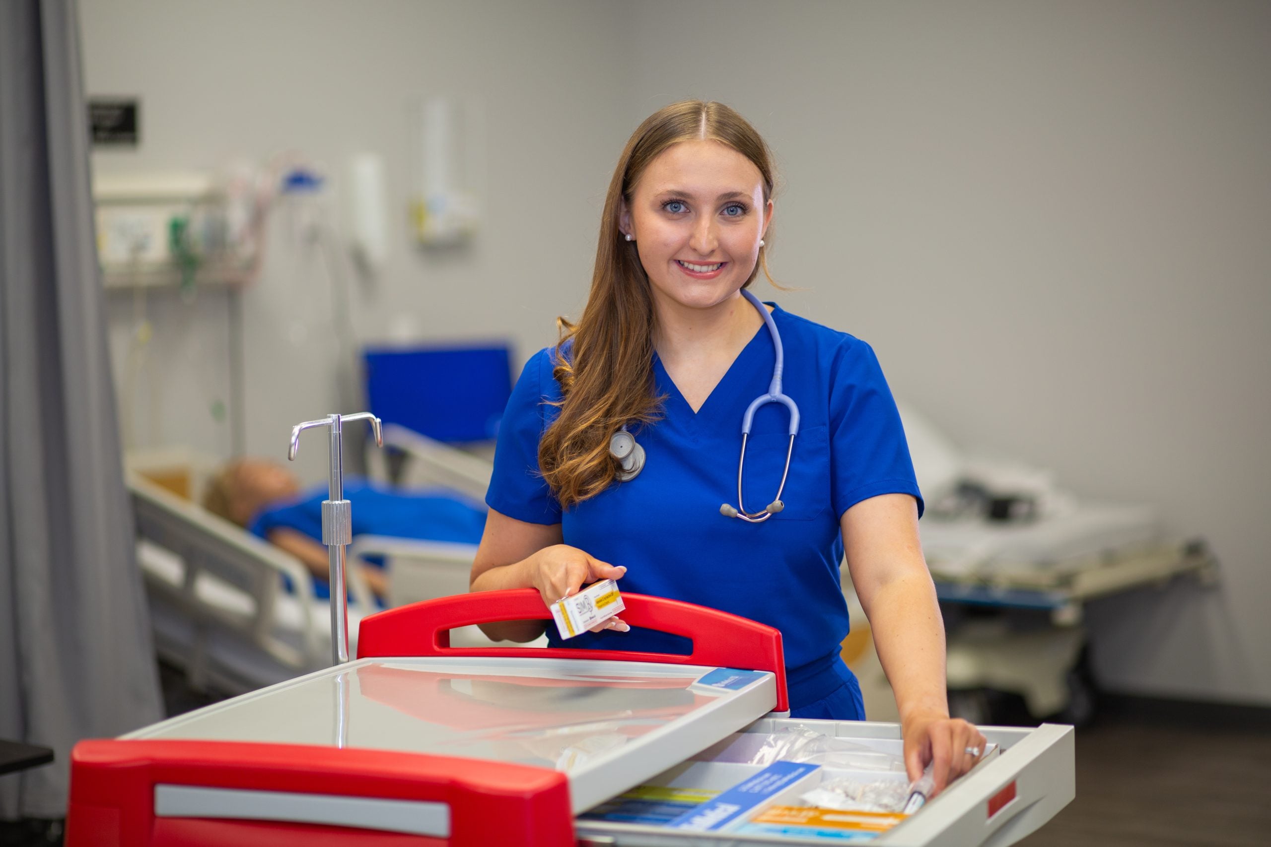 faulkner-university-nursing-student-standing-next-to-medical-cart-scaled