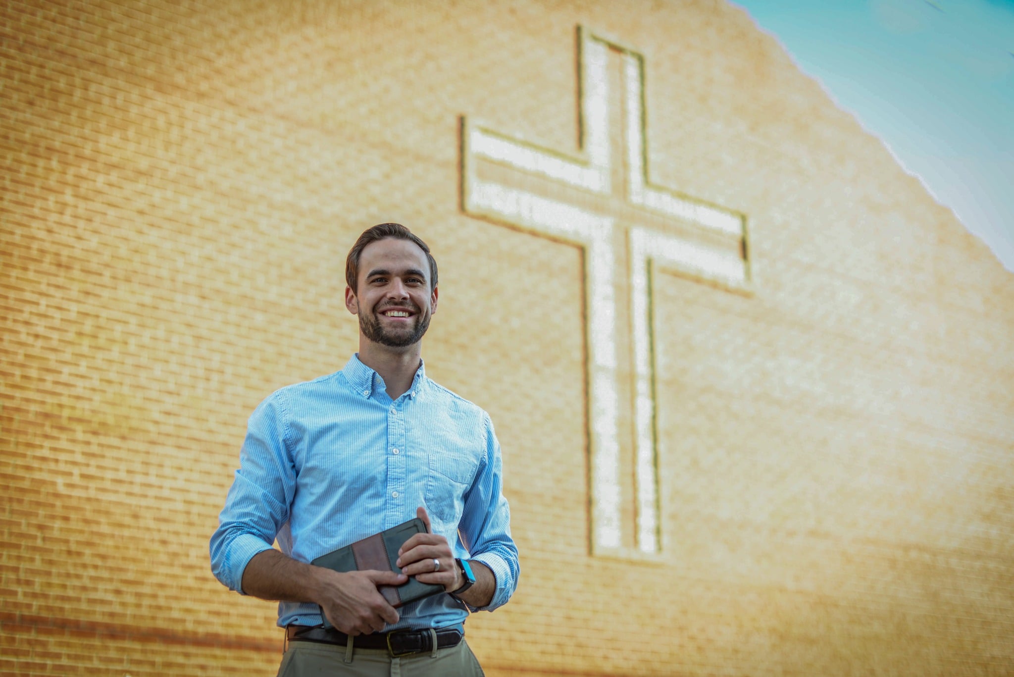 Bible_ManHoldingBible_CrossBehind