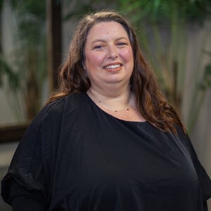 Woman with long dark hair smiling into camera wearing a black shirt.