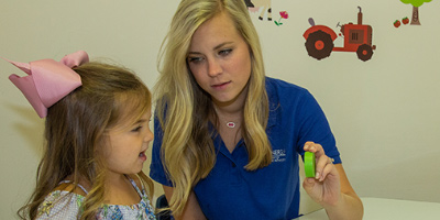 Health Sciences student showing a little girl a green block