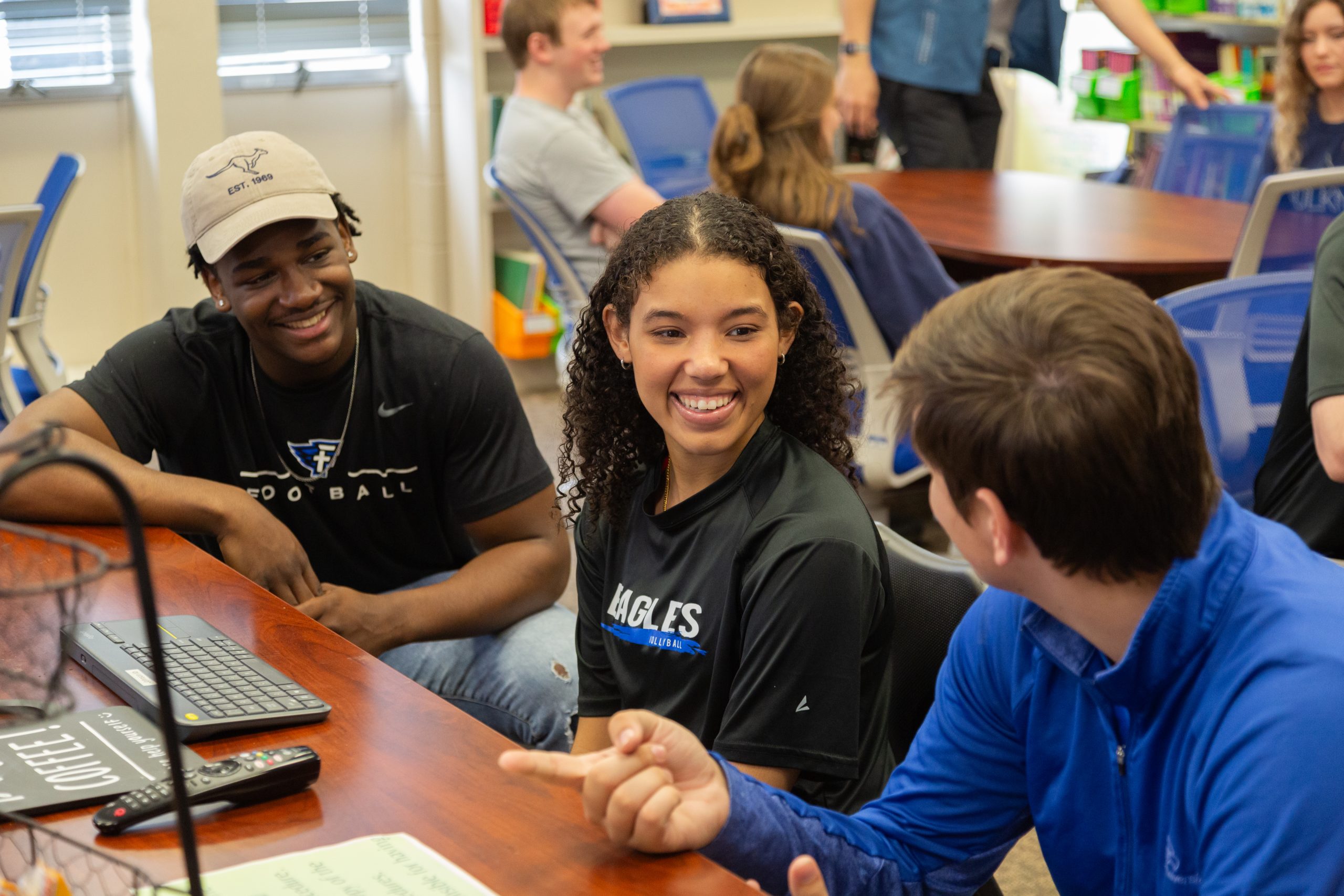 several students standing around table talking