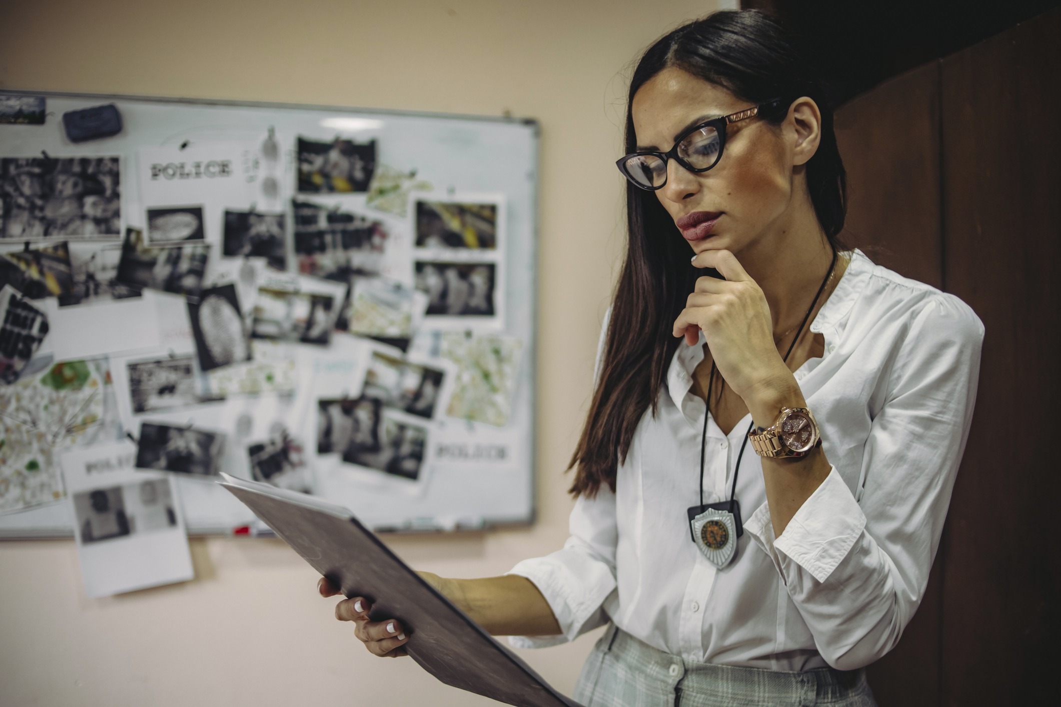 The lady detective is looking for clues about the case of a serious crime – – The hard work of a detective in the office – The detective in the office is working to gather evidence and clues in finding the killer