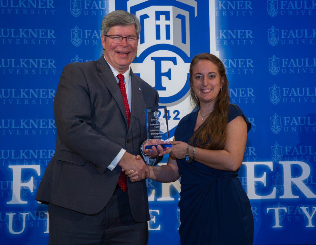 President Mitch Henry presents the Distinguished Alumna Award to Moriah Hagel.