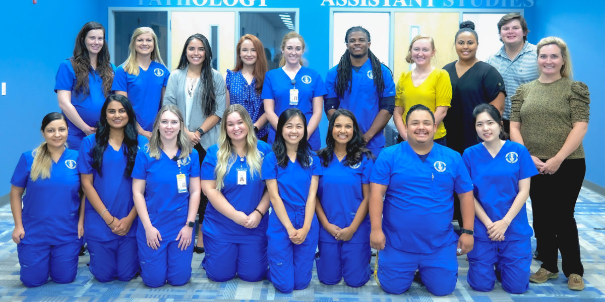 College of Health Sciences' Service Club students pose together in their bright blue scrubs.   