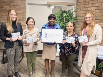 l-r, College of Health students, Jenna Bazil, Michelle Liu, Jessica Witherspoon with Family Sunshine Center, Tevri Tayip and Hannah Beckett pose with their artwork from Painting with a Purpose event.