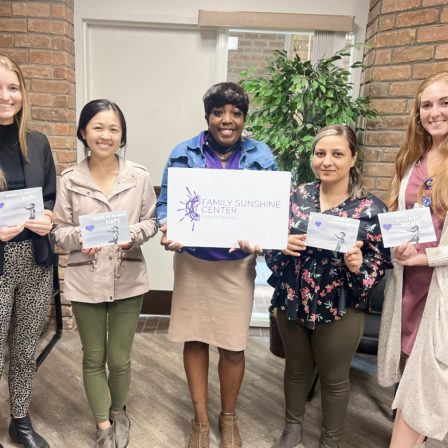 l-r, College of Health students, Jenna Bazil, Michelle Liu, Jessica Witherspoon with Family Sunshine Center, Tevri Tayip and Hannah Beckett pose with their artwork from Painting with a Purpose event.