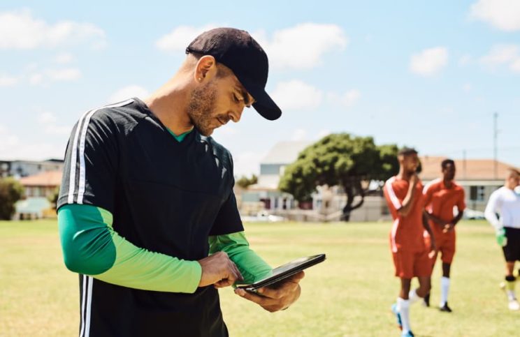 A soccer coach looks at a tablet