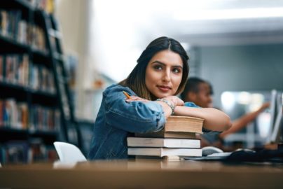 A student with a stack of books in a library