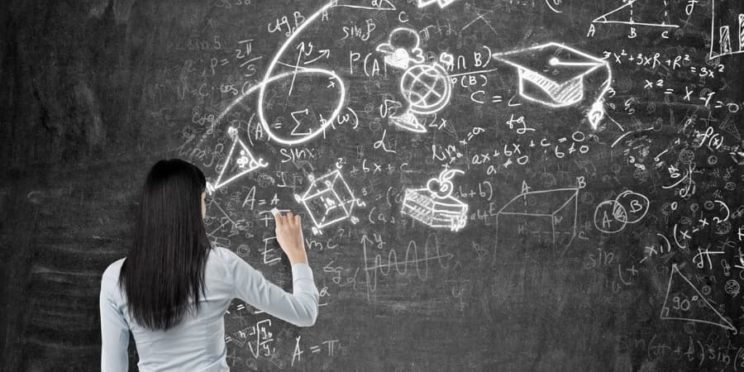 A young woman sketches on a chalkboard