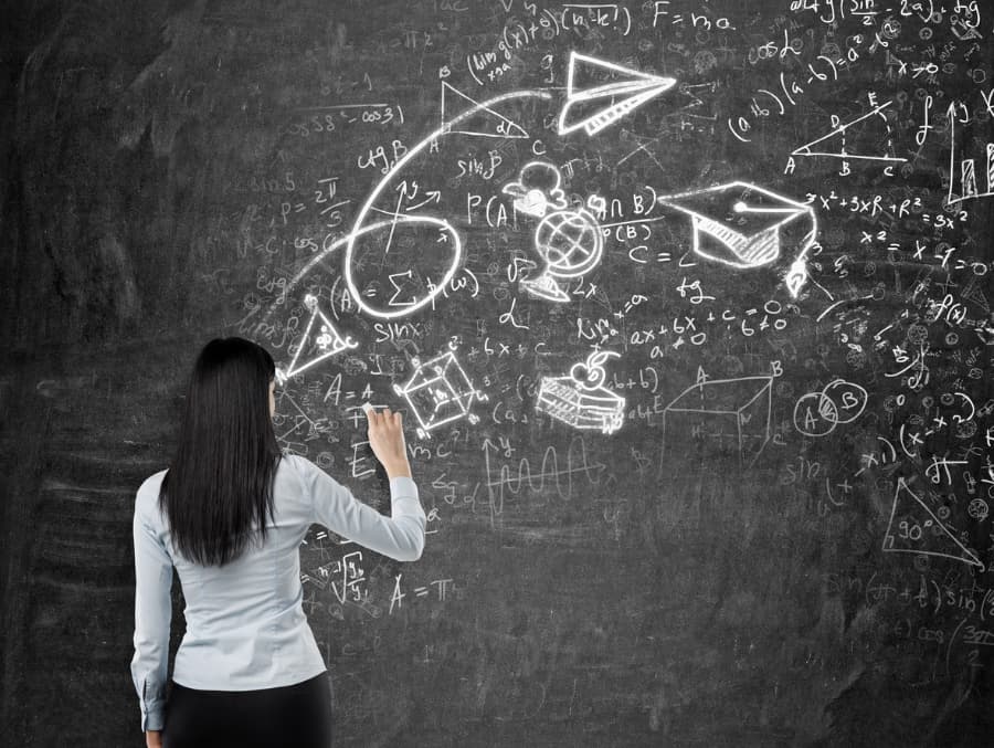 A young woman sketches on a chalkboard