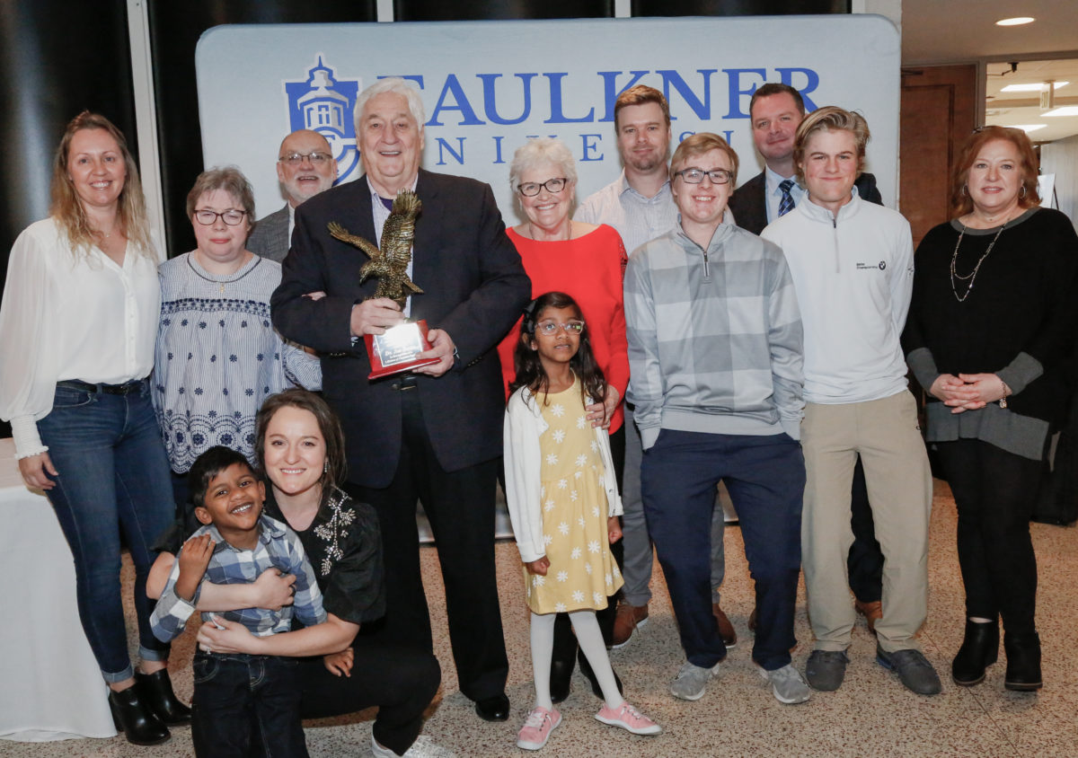 Joe Beam, Alumnus of the Year, stands with his award with his wife Alice by his side, surrounded by his family.