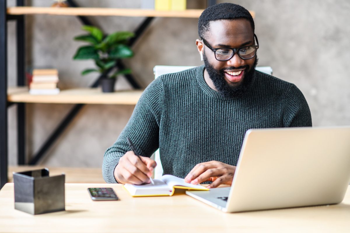 Adult student smiles at laptop screen in home office