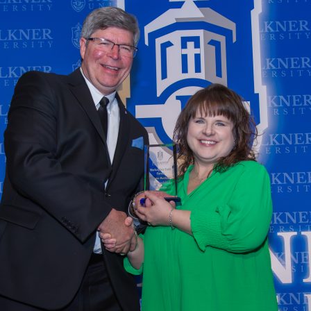 Allena Burbage receives the Distinguished Alumna Award from President Mitch Henry.