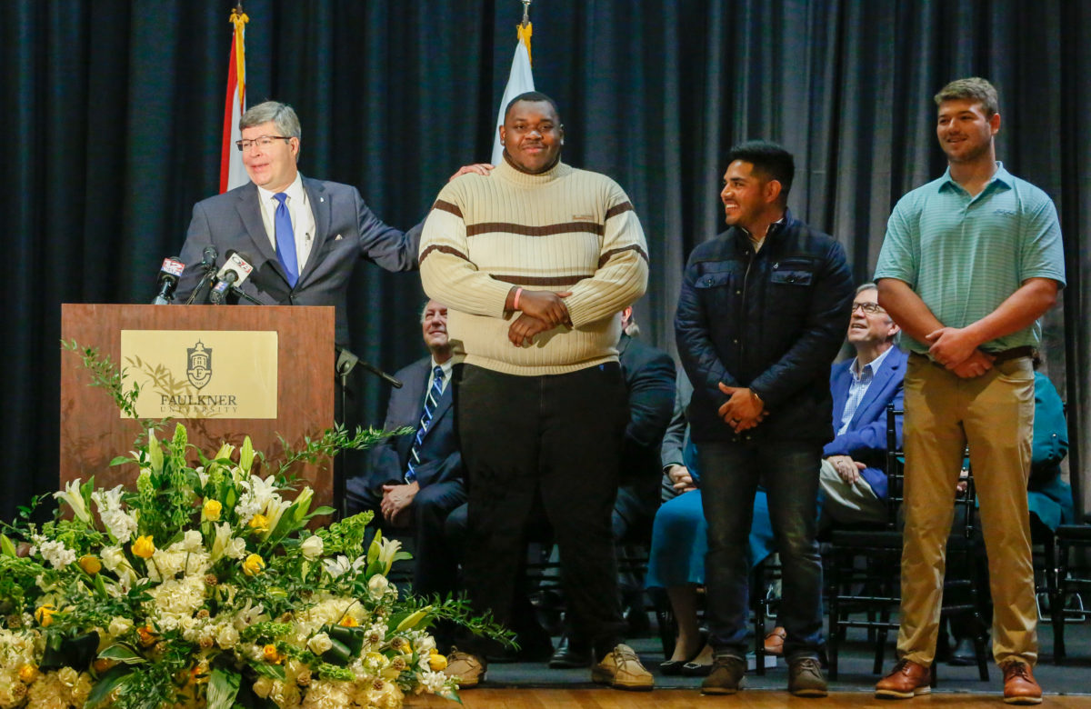 Mitch Henry stands on stage with his students, Quanterio Stokes, Jonathan Villa and Travis Pate.