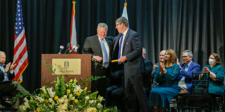 President Mike Williams passes a gold-colored baton to President-elect Mitch Henry following the announcement of Henry's selection as Faulkner's 9th president.