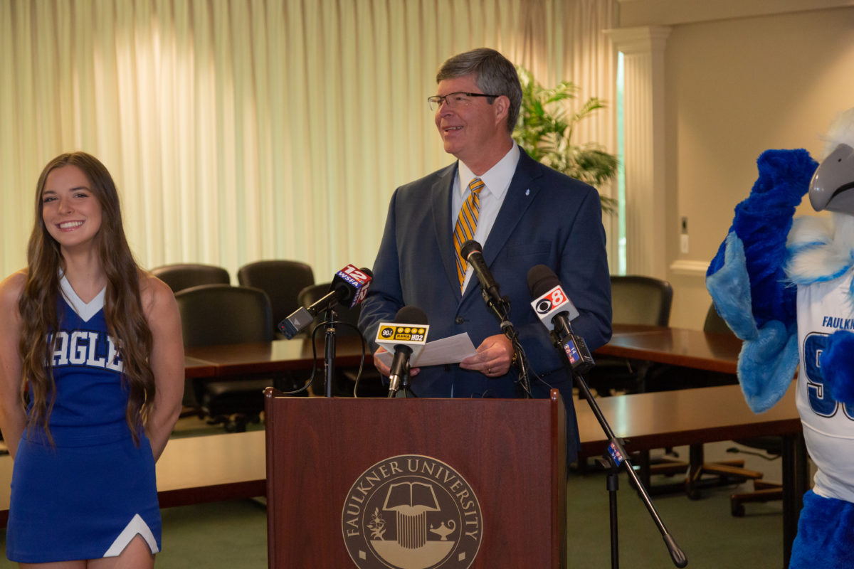 Faulkner University President Mitch Henry announces Drew Brees as the university's 2023 Benefit Dinner speaker with the university's Eagle mascot, Royal on the right and a member of the cheer team on the left.