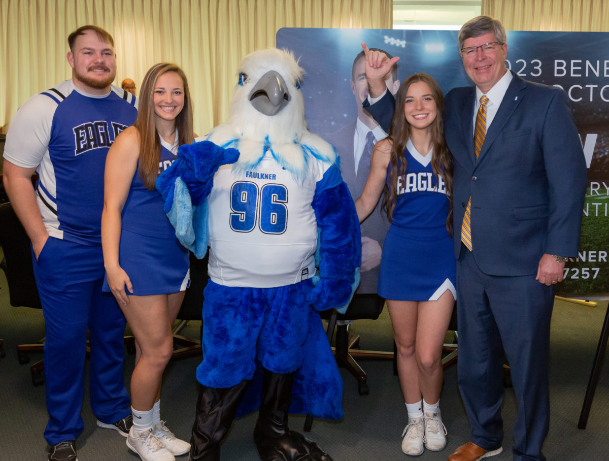 Members of the Faulkner University Cheer team pose with mascot Royal and President Mitch Henry.