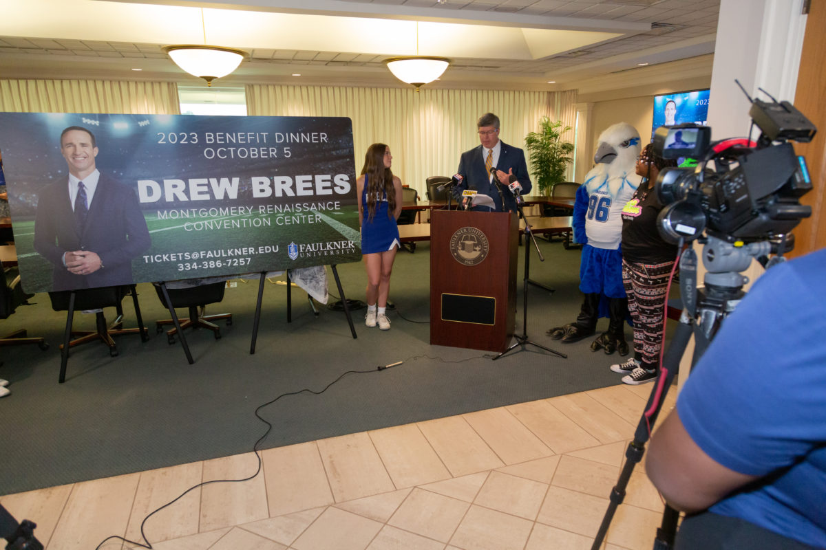Faulkner University President Mitch Henry announces Drew Brees as the university's 2023 Benefit Dinner speaker with the university's Eagle mascot, Royal and SGA officer Destini Gibson on the right.