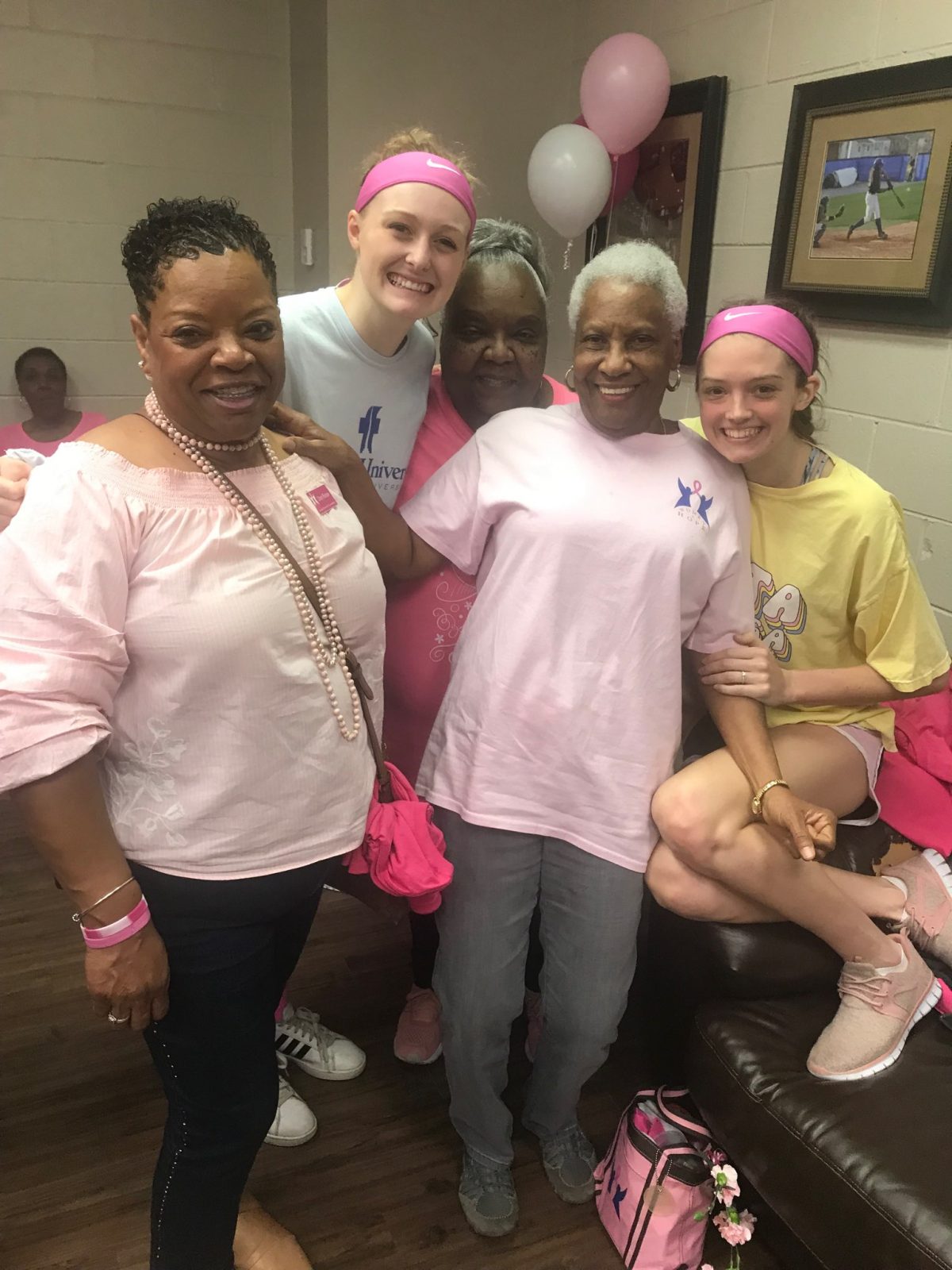 Breast Cancer survivors pose with the Faulkner Women's Basketball team during their PinkOut game in 2020.