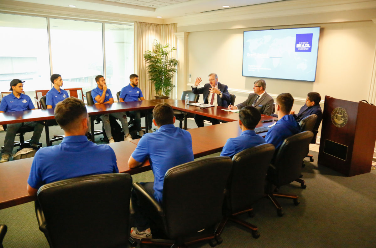 En la cabecera de la mesa, Nestor Forster Jr., embajador de Brasil en los Estados Unidos, se sienta junto al presidente Mitch Henry y al entrenador en jefe de fútbol masculino Gabriel De Queiroz mientras habla con los estudiantes brasileños de Faulkner durante su visita el 25 de agosto de 2022. .