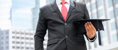 Business professional holding graduation cap.