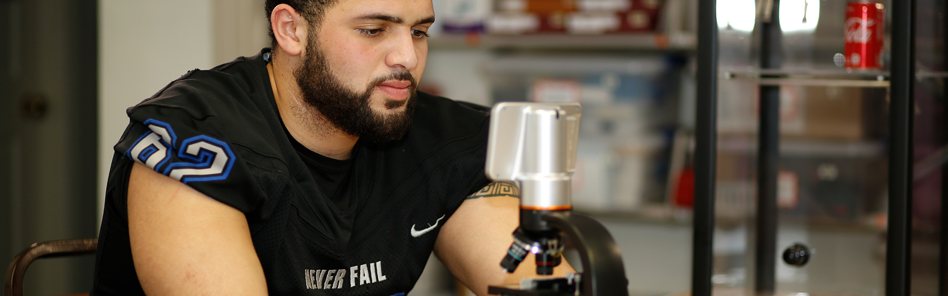 CJ Student athlete in criminal justice major studying with microscope