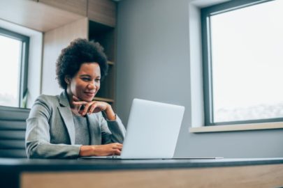 Woman looking at laptop while sitting in modern office