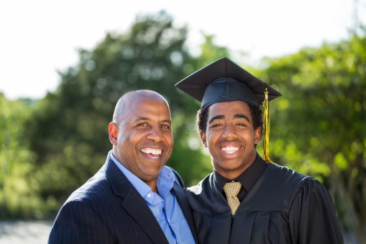 College graduate in robe poses with father