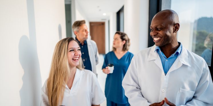 Doctor and assistant smiling while talking and walking