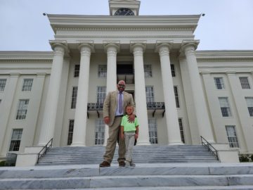 DA Jeremy Duerr stands on the steps of the Capitol, with his son Stephen.