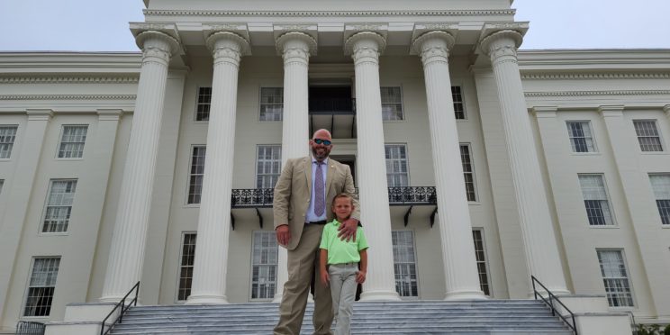 DA Jeremy Duerr stands on the steps of the Capitol, with his son Stephen.