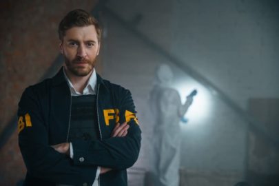 FBI agent standing with arms crossed at crime scene