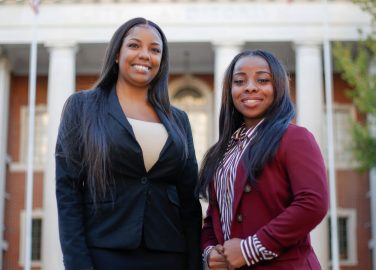 Faulkner Law graduate Aigner Kolom, left poses with Faulkner Law student Iesha Brooks in front of Montgomery City Hall.