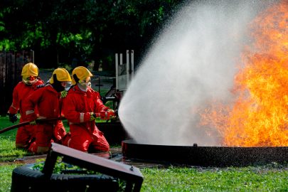 Firefighters with water hose use water to put out fire during training outside