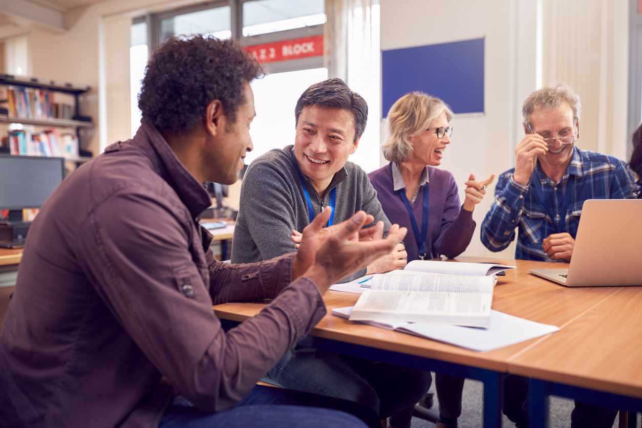 Four graduate students sitting at table in library and working on group project