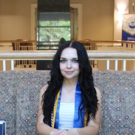 Sinclair Drysdale sits on a couch with her graduation stole and cords.
