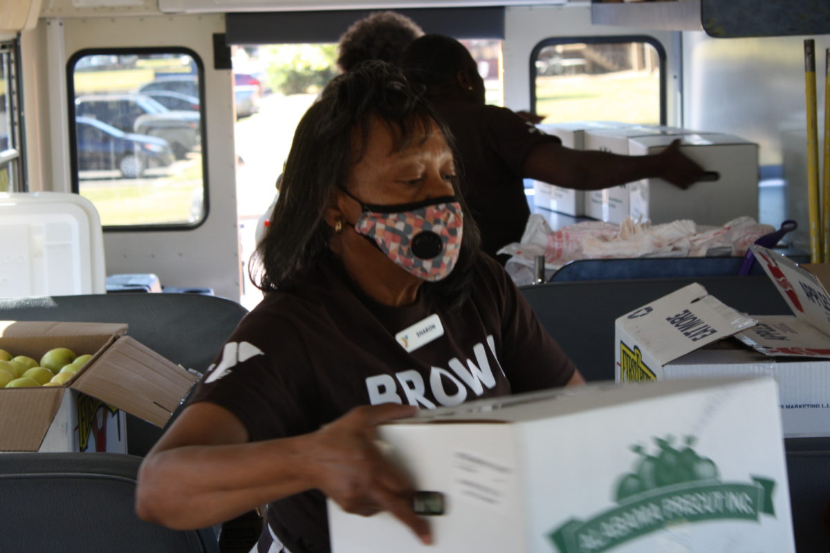 A woman inside the YMCA Brown Bag Bus loads and organizes food donated from Faulkner's Culinary Management team. 
