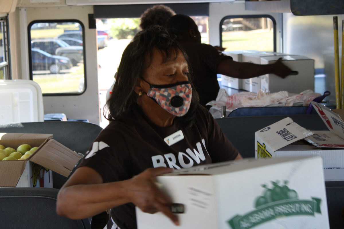 A woman inside the YMCA Brown Bag Bus loads and organizes food donated from Faulkner's Culinary Management team.
