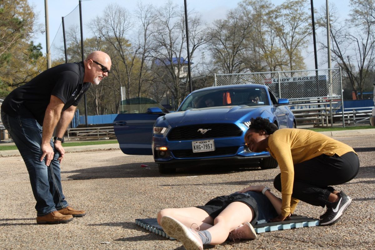 Student assesses the responsiveness of her "unconscious" peer during a First-Aid CPR class demonstration. 