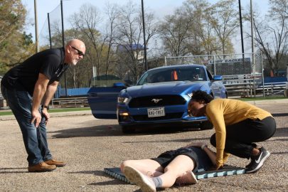 Student assesses the responsiveness of her "unconscious" peer during a First-Aid CPR class demonstration.