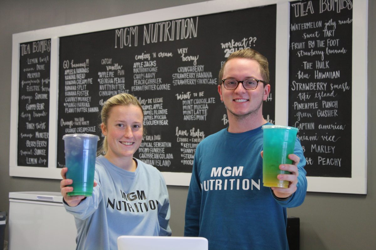 Brianna Cagle, left and Logan Wallace hold up drinks in their store, MGM Nutrition.