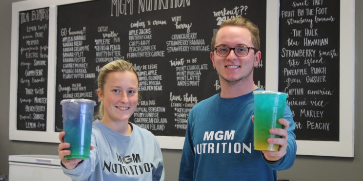 Brianna Cagle, left and Logan Wallace hold up drinks in their store, MGM Nutrition.
