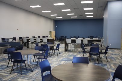 Renovations of the College of Health Sciences include blue painted walls, blue and gray patterned carpeting and tables and chairs in the lobby area.